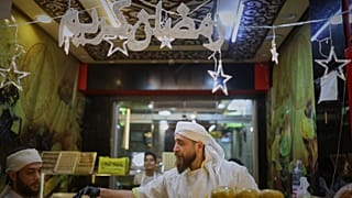 بائع يعتني بكشكه ذو الإضاءة الساطعة المليء بحلويات رمضان في دمشق، الخميس 19 فبراير 2026.