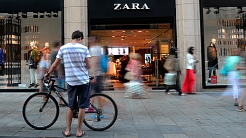 أشخاص يمرون سيراً أمام متجر "زارا" في برشلونة، إسبانيا، في أغسطس 2021.