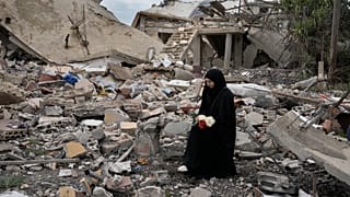 امرأة لبنانية تحمل باقة من الزهور وهي تجلس على أنقاض منزل مدمر بسبب الهجوم الجوي والبري الإسرائيلي، في عيتا الشعب، قرية حدودية لبنانية مع إسرائيل، جنوب لبنان، 