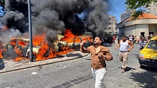 Persone corrono davanti ad auto bruciate colpite da un raid aereo israeliano nella città portuale meridionale di Sidone, in Libano, mercoledì 10 giugno 2026.