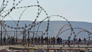 ARQUIVO - Migrantes resgatados a sul de Creta caminham após chegarem ao porto de Lavrio, Grécia, a 10 de julho de 2025