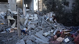 شبان فلسطينيون ينقذون بعض مقتنياتهم من مبنى دمرته غارة جوية إسرائيلية في مخيم المغازي للاجئين