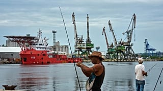 Un pescatore prepara la canna da pesca davanti alla nave della Marina colombiana ARC Caribe ormeggiata a un molo dell'Avana, 12 giugno 2026