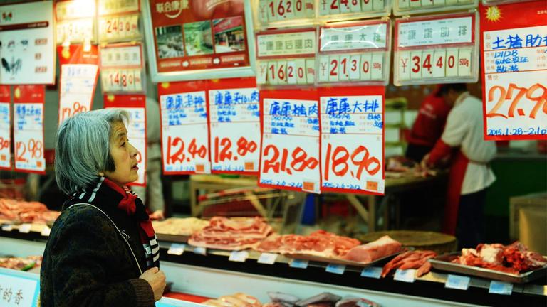 Kundin zwischen Preisschildern in einem Supermarkt, Hangzhou, China.