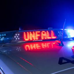 Schild auf einem Polizeiwagen warnt vor einem Unfall