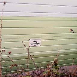 Ein Schild mit einem Lurch weist auf einen Kleintierdurchgang der Lärmschutzwand einer Bahnstrecke hin