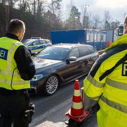 Zwei Polizisten stoppen mit der Kelle ein heranfahrendes Auto.