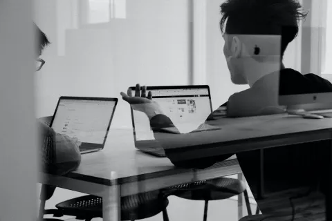 People working on laptops, seen through glass