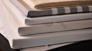 A close up of a stack of mattress toppers of different designs and thicknesses