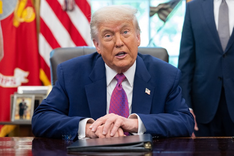 Donald Trump sits at his desk in the Oval Office of the White House.