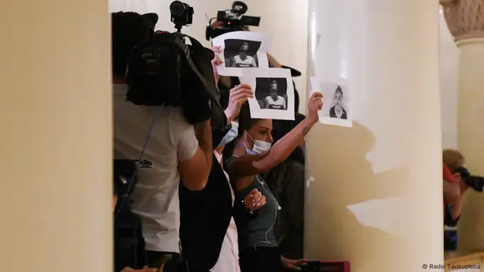 Protesters hold up photos of victims in the Georgian Parliament