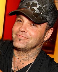 close-up of Binzer wearing a dark shirt and patterned baseball cap and smiling at camera