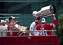 Photographie montrant Patrick Kane qui brandit la Coupe Stanley et Jonathan Toews qui tient le trophée Conn-Smythe.