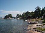 Vy från hamnviken med Esbo segelförenings klubbhus till vänster. Till höger den gamla fiskeboden. Längst till höger skymtar den äldsta byggnaden som hört till fiskarhemmanet, vars äldsta delar är från 1700-talet.