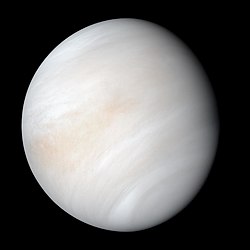 Venus in approximately true-color, a nearly uniform pale cream, although the image has been processed to bring out details.[૧] The planet's disk is about three-quarters illuminated. Almost no variation or detail can be seen in the clouds.