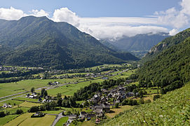 Photo d'un paysage montrant une vallée entourée de montagnes boisées.