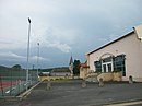 Le terrain de tennis, la salle des fêtes, en arrière-plan, le stade de football et l'église