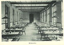 Photographie du réfectoire du lycée : des tables alignées et des chaises.