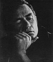 Black and white image of a man with his chin resting the thumb of his hand