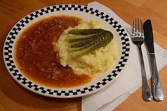 Gehacktesstippe in dunkler Sauce an Kartoffelbrei mit Gurkenfächer