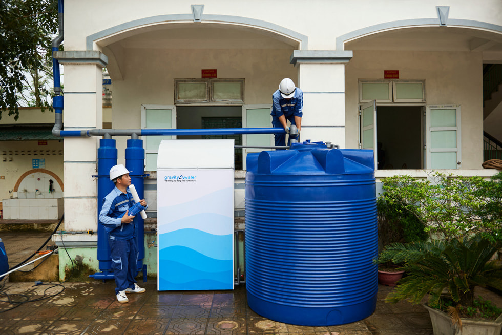 Seseorang sedang menginspeksi sistem Gravity Water,  sementara satu orang lain melihatnya.