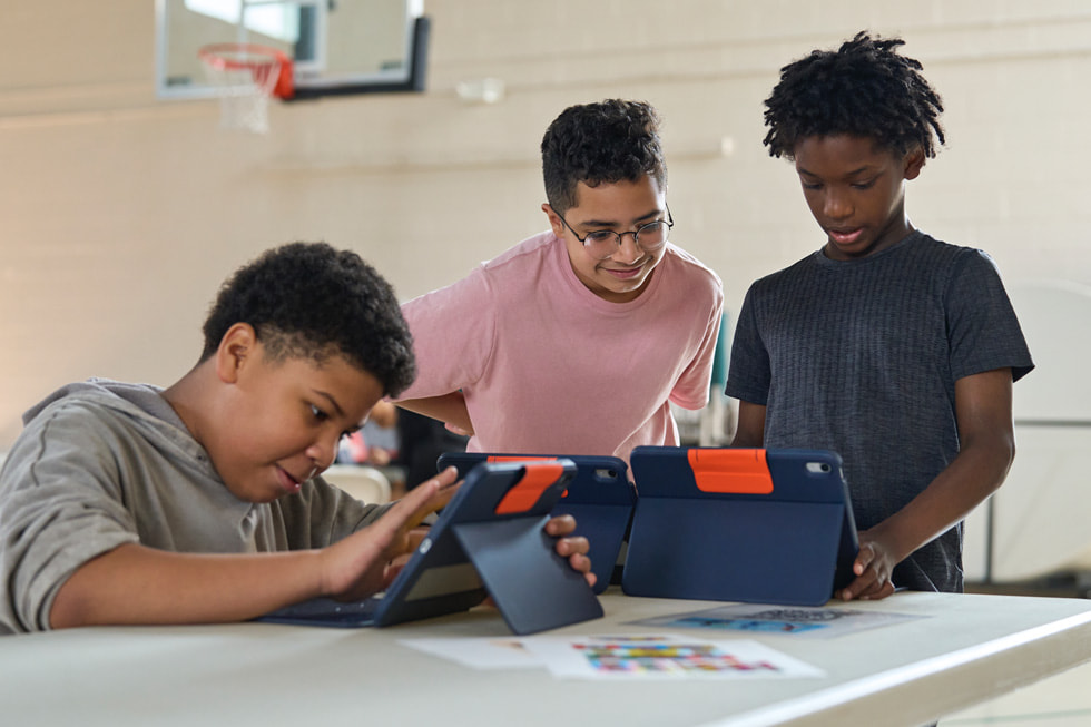 Seorang instruktur 4-H bekerja dengan pelajar muda menggunakan iPad di kamp STEM Explorers.