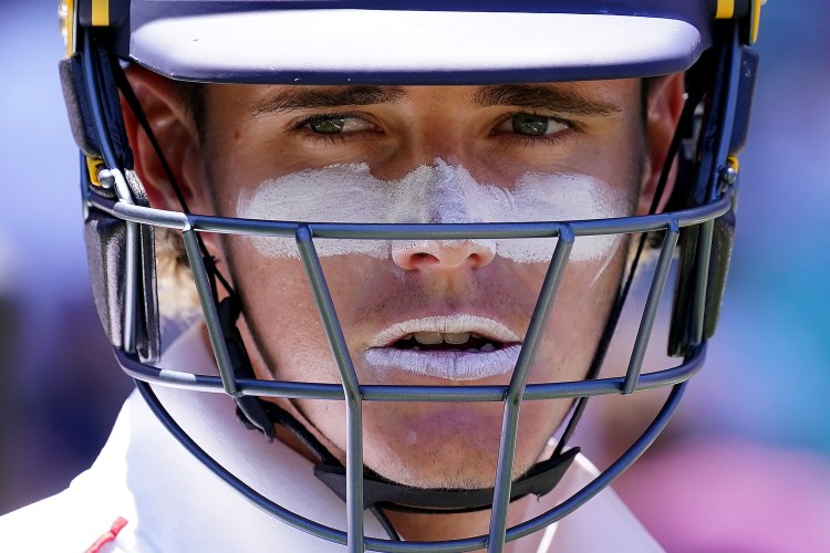 England’s Jacob Bethell wearing a helmet, with white zinc sunscreen on his cheeks and lips.