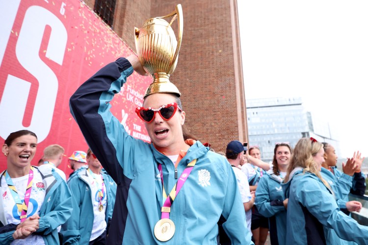 Emily Scarratt celebrating England's World Cup victory with the trophy on her head.
