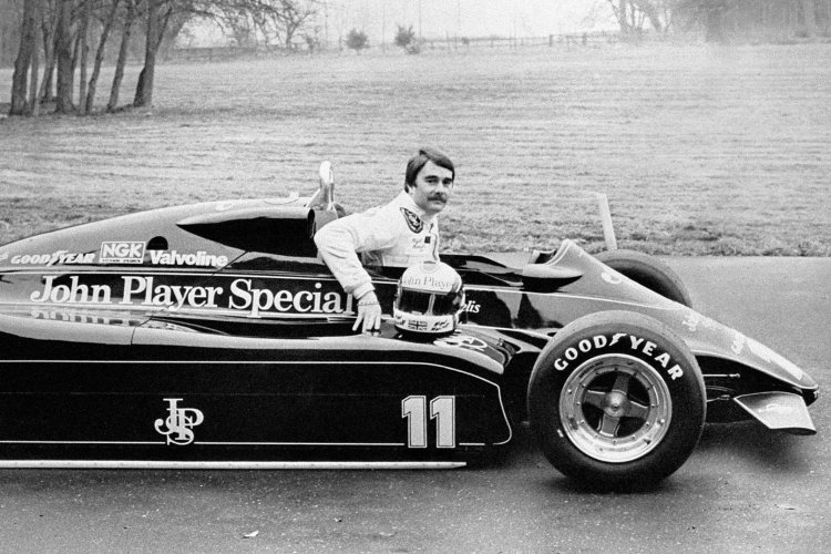 Black and white photo of a Formula One driver posing in a Lotus Grand Prix car.