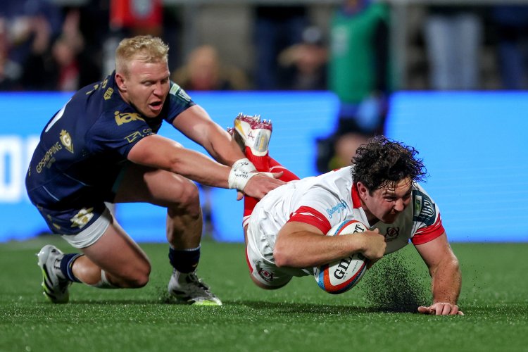 Tom Stewart of Ulster scores a try while being tackled by an opponent during a rugby match.