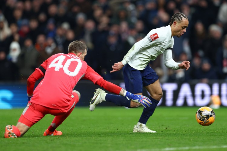 Xavi Simons of Tottenham Hotspur dribbles the ball past Marco Bizot of Aston Villa.