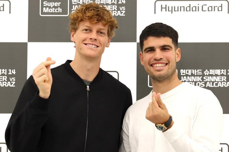 Jannik Sinner and Carlos Alcaraz smiling and making heart gestures at the Hyundai Card Super Match press conference.