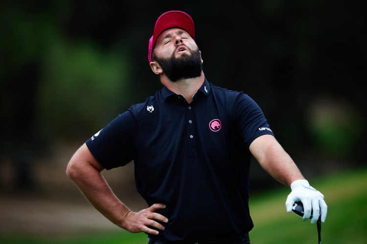 Jon Rahm in a black shirt and pink hat reacting in distress at the Open de España.